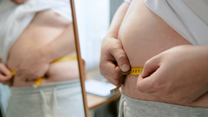 Übergewichtiger Mann misst seinen Bauchumfang als Teil der Trainingskontrolle