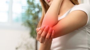 Frau hält schmerzenden, geröteten Ellbogen; Entzündungen im Körper erhöhen den Cortisolspiegel.