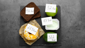 Verschiedene Lebensmittel mit Post-its, die Kalorienangaben zeigen – Ernährung beim Abnehmen