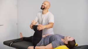 Daniel vom Fitlab Stuttgart beim gemeinsamen Dehnen mit einer lachenden Kundin.