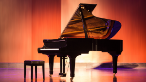 Hochwertiger, schwarzer Konzertflügel (ähnlich Steinway & Sons) in einem prachtvollen Saal, Symbol für Luxus und anspruchsvolle Fertigkeiten.