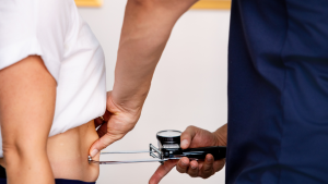 Detailaufnahme einer Körperfettmessung am Bauch zur Analyse von stressbedingten Fetteinlagerungen.