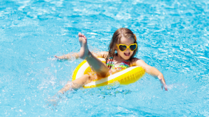 Kind plantscht fröhlich im Pool mit gelbem Schwimmring – echte Bewegung statt Bildschirmzeit