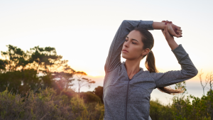 Frau dehnt sich bei Sonnenaufgang in der Natur – Morgenroutine Frühaufsteher Fitlab Stuttgart