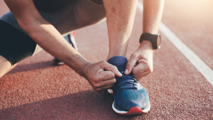 Sportler bindet Laufschuhe auf der Tartanbahn – Morgensport Frühaufsteher Fitlab Stuttgart
