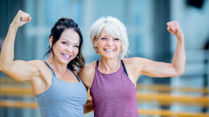 Zwei sportliche Frauen über 50 zeigen lachend ihre Muskeln – Krafttraining für Frauen Fitlab Stuttgart