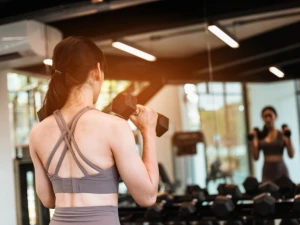 Frau trainiert mit Kurzhanteln im Fitnessstudio