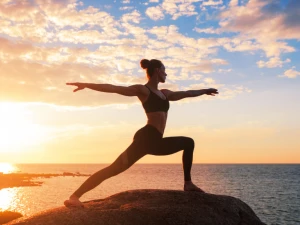 Frau in einer Yoga Pose bei Sonnenuntergang am Meer